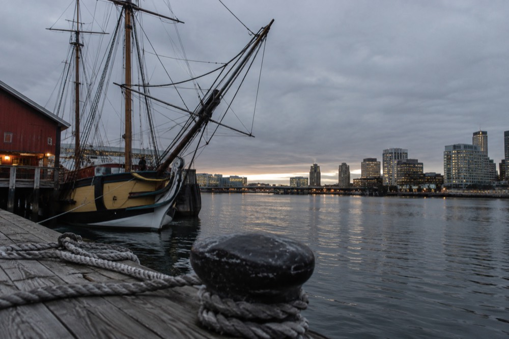 Replica sailing ship moored at a museum pier on Boston Harbor at dusk