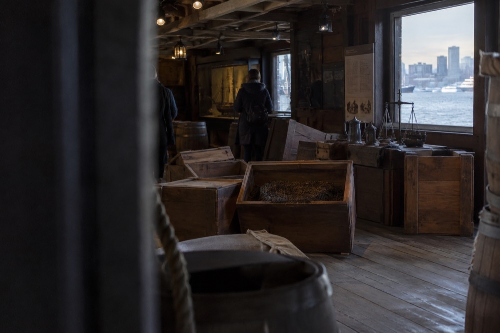 Museum interior with wooden tea chests and eighteenth-century artifacts under display lighting