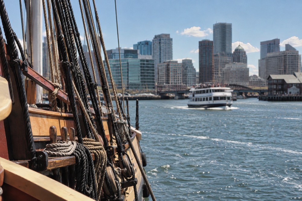 Boston harbor waterfront with a cruise boat and city skyline behind