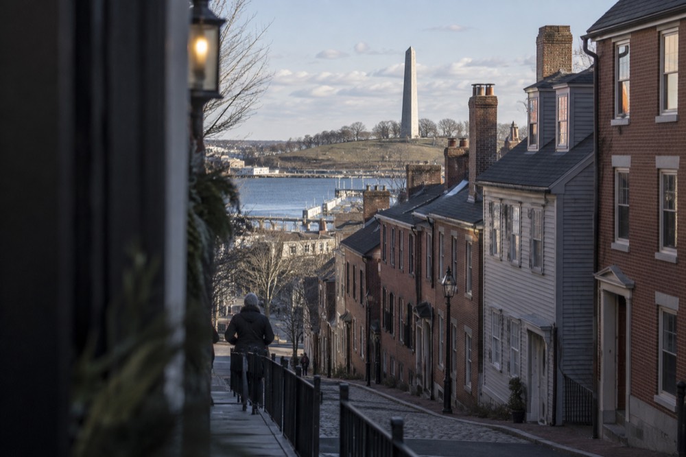 A tall granite obelisk rising above a green slope in Charlestown