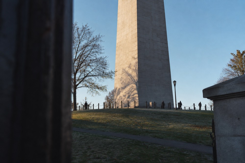 The base of a granite obelisk seen from below against a blue sky