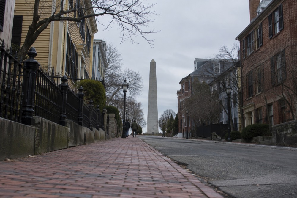 A red brick walking trail line leading up a residential street toward an obelisk