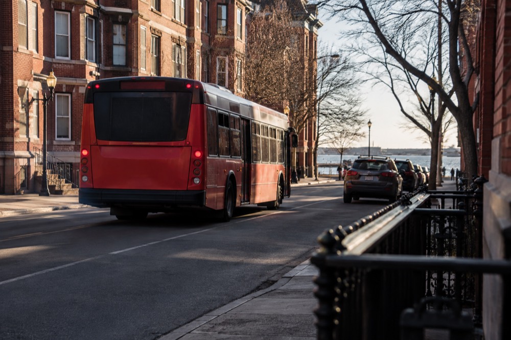 A red MBTA bus on a city street in South Boston with brick rowhouses behind it