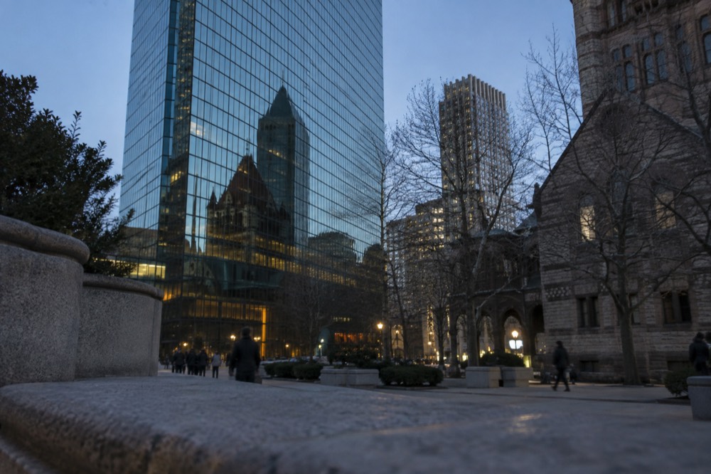 The reflective glass facade of the Hancock tower mirroring Trinity Church on a clear day