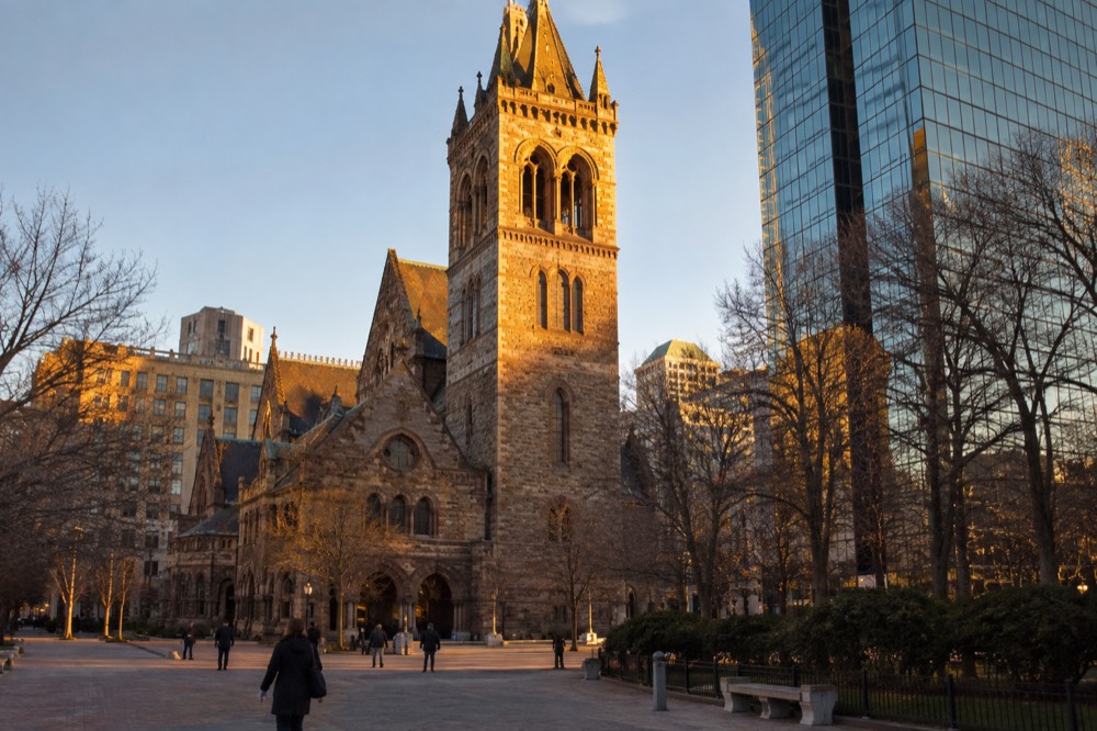 Late afternoon sunlight on Trinity Church's stone tower and roof seen from the plaza