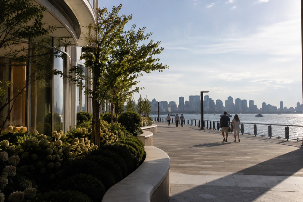 Visitors walking along the landscaped harborwalk outside Encore Boston Harbor on a sunny afternoon