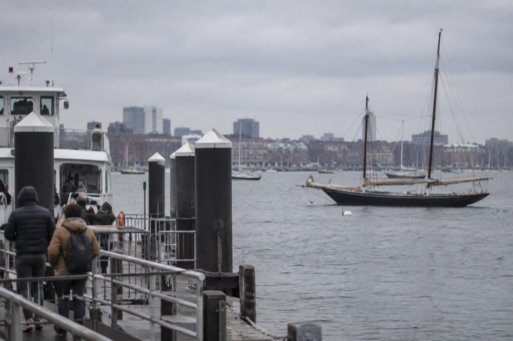 A ferry dock at Long Wharf with Boston Harbor and a moored sailboat in the background