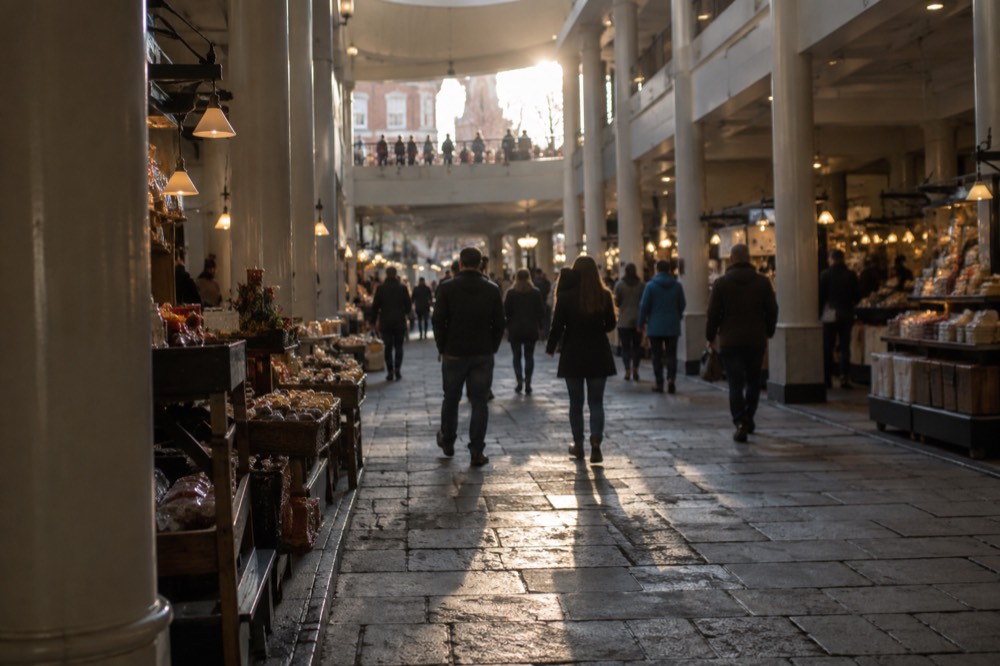 Visitors walking through the ground-floor market hall of Faneuil Hall with stone floors and stalls
