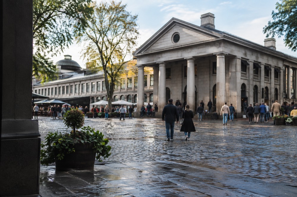 The granite facade and Doric columns of Quincy Market with crowds in the cobblestone plaza