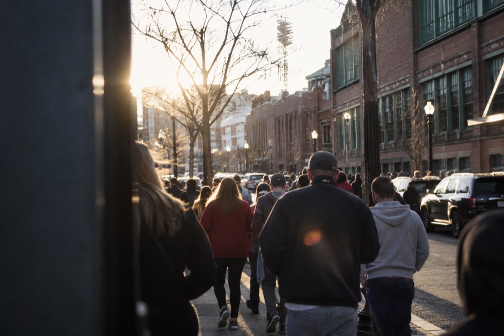A crowd gathering outside the ballpark gates on a busy Boston street before a game