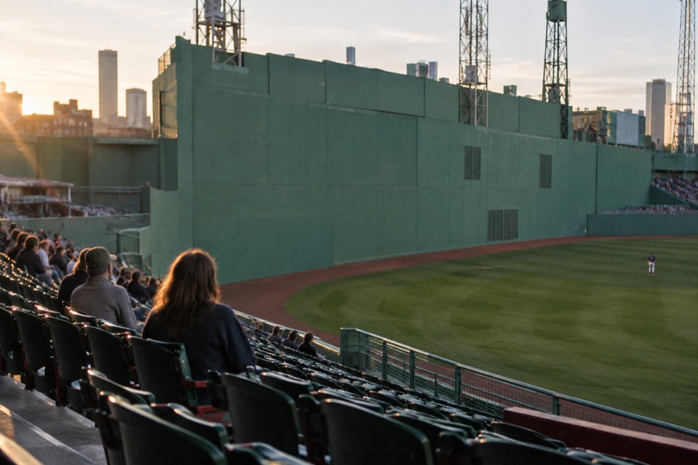 A close view of a ballpark's green wall in left field with seats in front of it