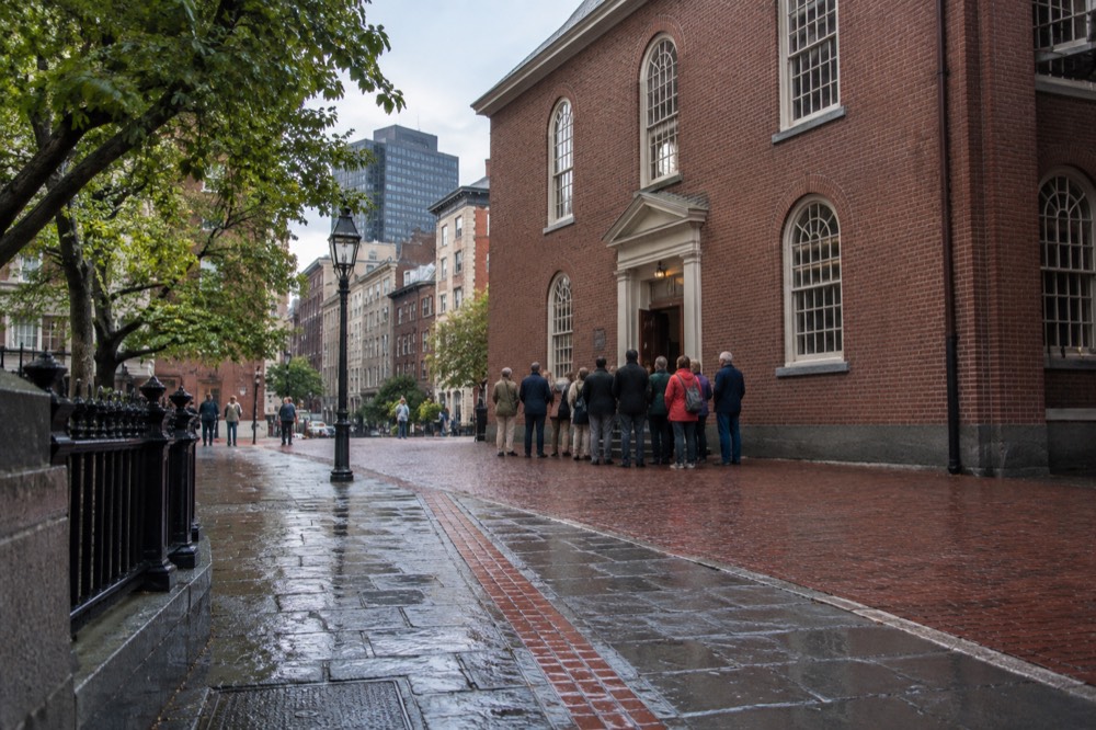 Guided tour group gathered outside an old brick meeting house on the Freedom Trail