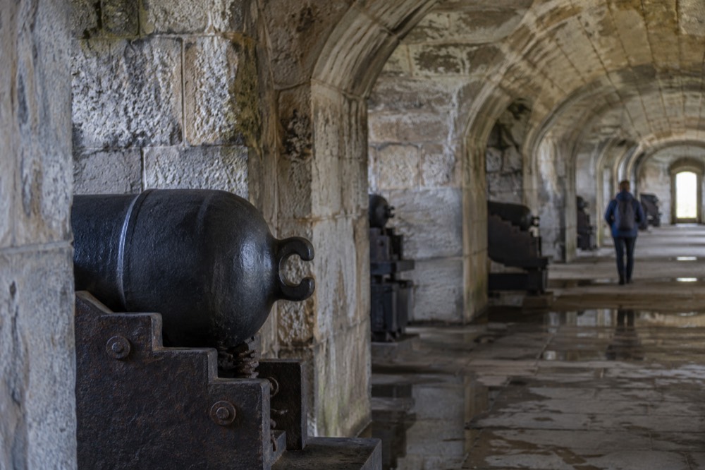 A shaded casemate corridor inside Fort Warren with arched granite ceilings