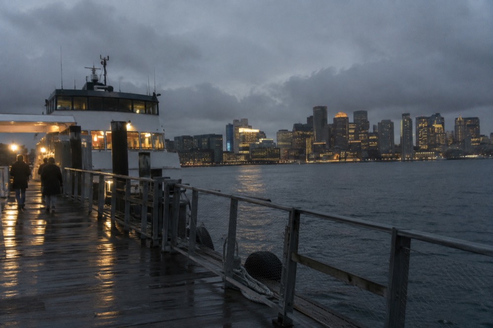 A ferry dock at dusk with the city skyline lit across the harbor