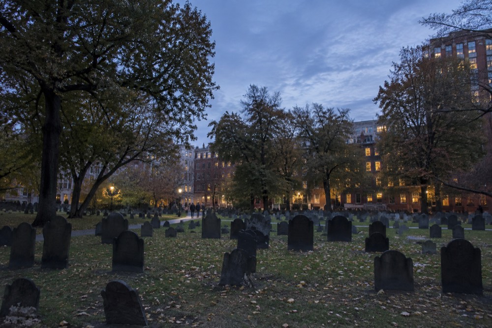 Rows of old slate slabs and leafy trees inside a historic Boston burying ground