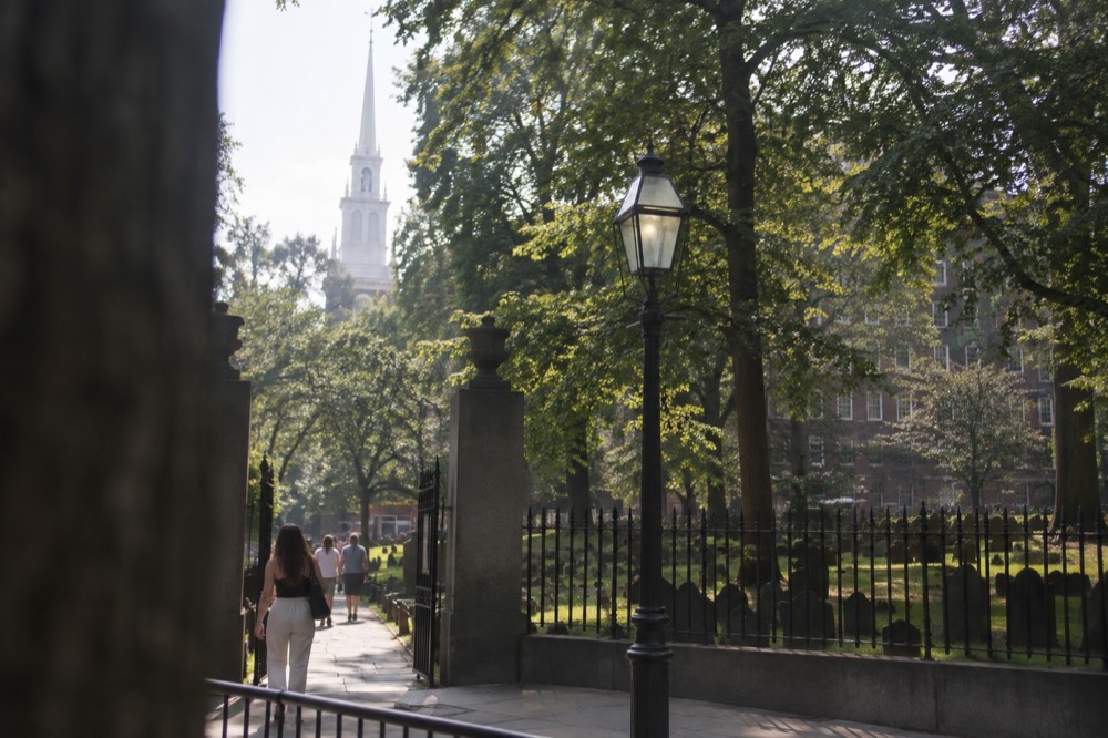 The historic burying ground gate on Tremont Street with Park Street Church rising behind trees