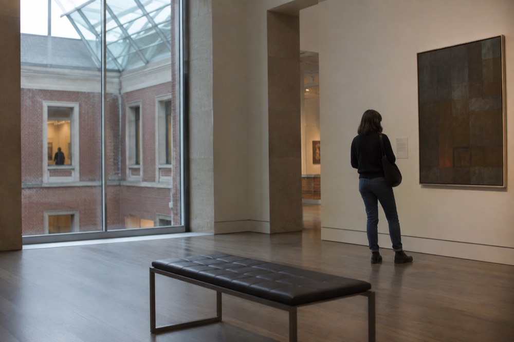 A visitor reading a label beside a painting in a gallery