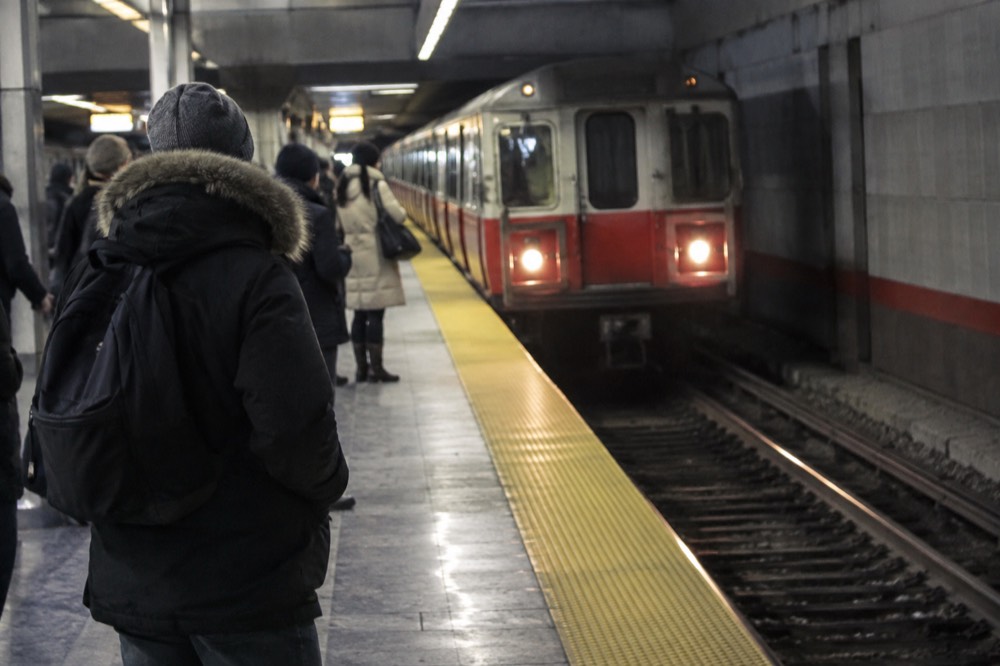 A red subway train arriving at an underground station platform with passengers waiting