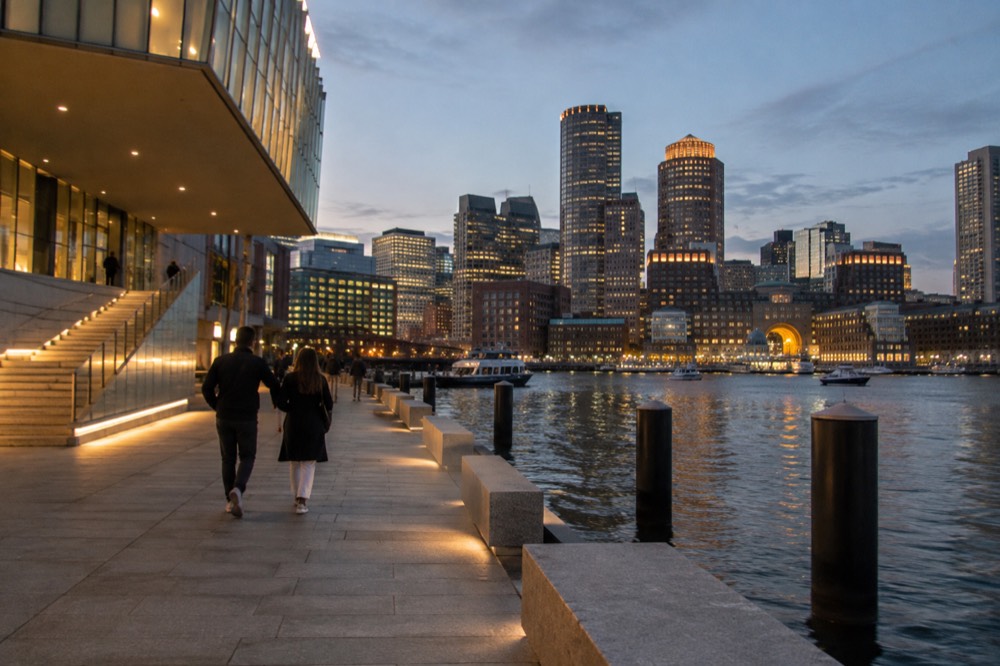An evening view of lit towers and a waterfront plaza near a museum