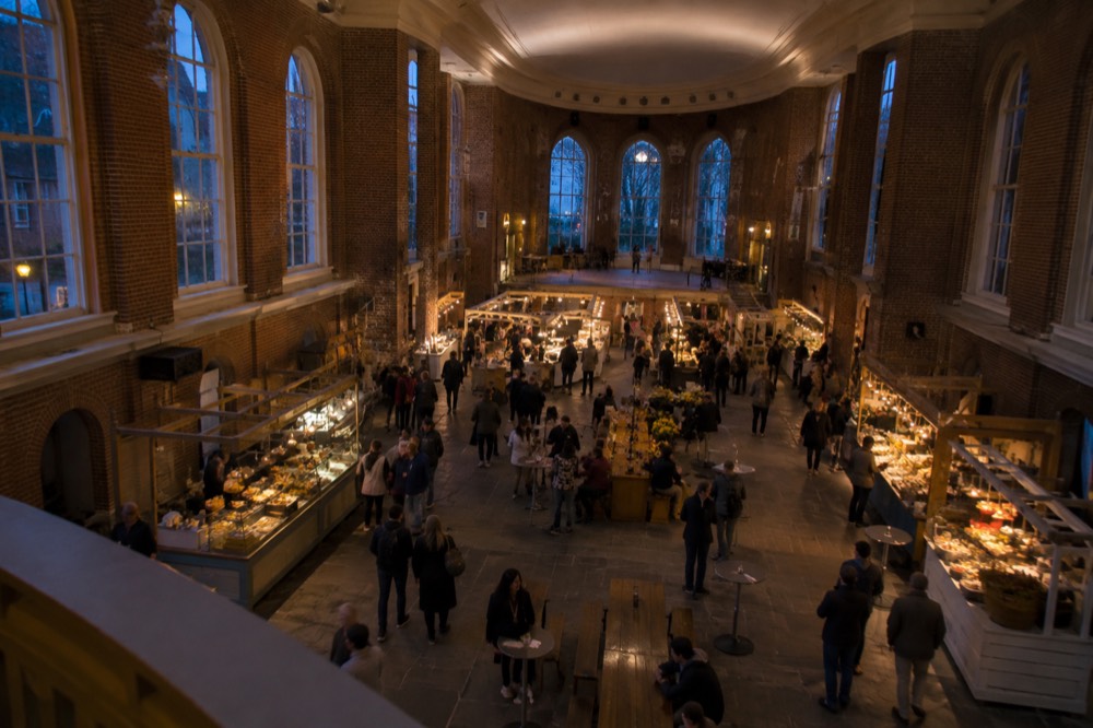 Busy brick market hall with food stalls and visitors walking