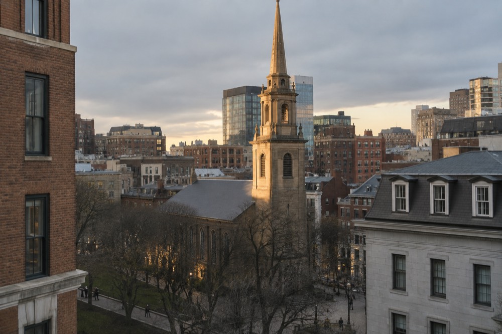 Church tower lit by warm evening light above city rooftops