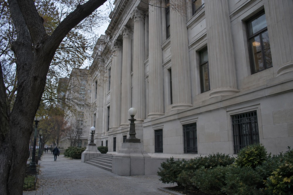 The exterior of a neoclassical publishing house building on a Boston street with trees