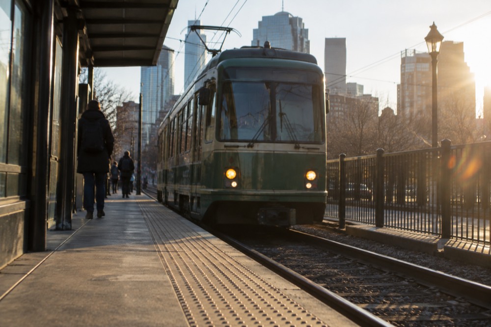 A green line trolley arriving at an outdoor Boston station platform