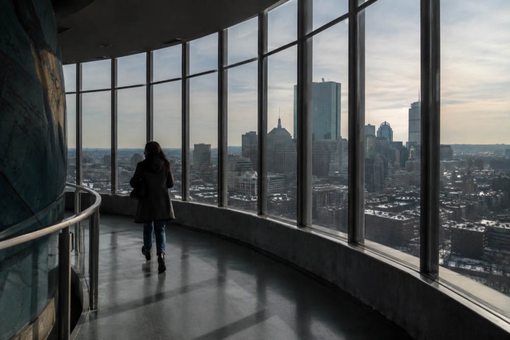 A city skyline seen from a high indoor observation deck with large windows