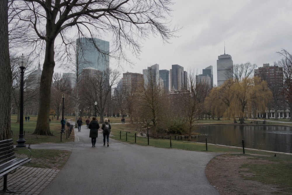 Glass-walled museum entrance on a Cambridge street with the Boston skyline across the river