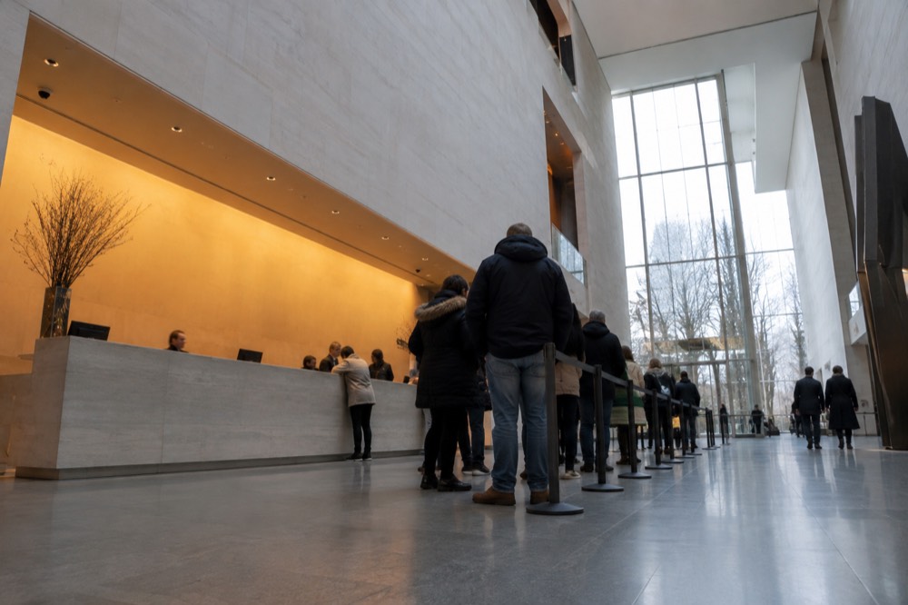 A ticket desk in a museum lobby with a queue of visitors waiting
