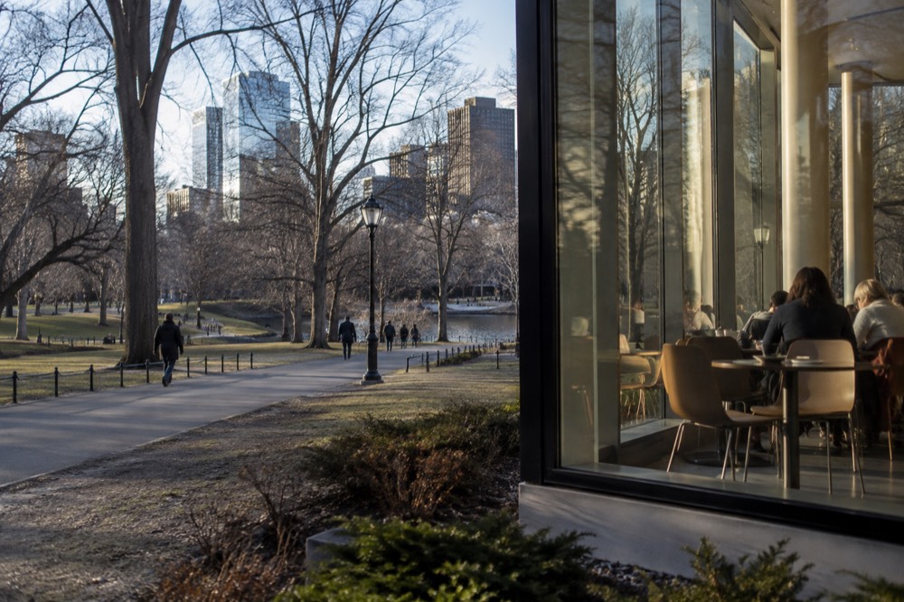 A museum cafe with people seated at tables under large windows