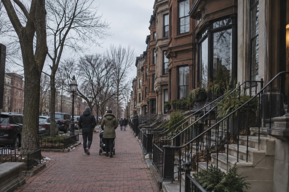 Family walking with a stroller along a wide brick sidewalk