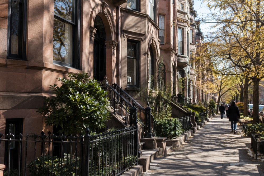 Brownstone facades glowing under streetlights in the evening