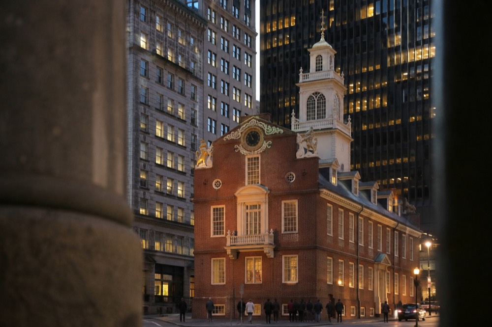 The Old State House seen from across State Street at dusk with office windows lit behind it