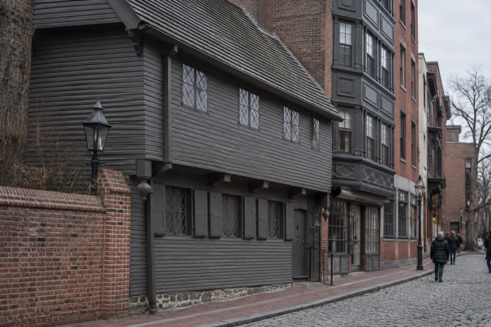 The dark timber facade of the Paul Revere House on a narrow North End street