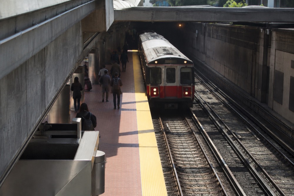 A red MBTA subway train arriving at a downtown Boston platform