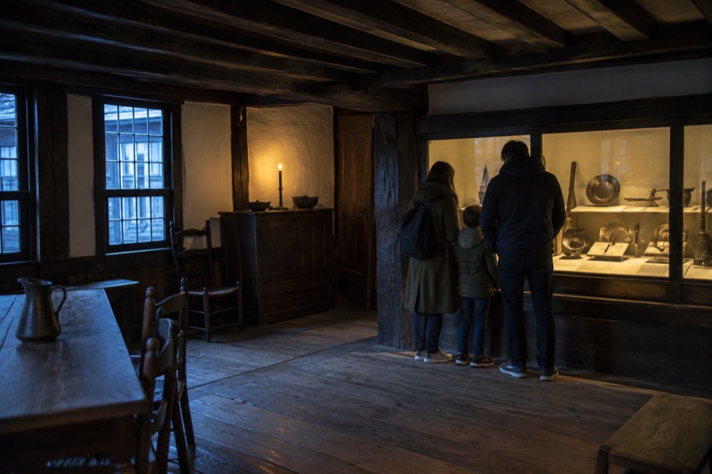 A family looking at a historic display case inside a small museum room