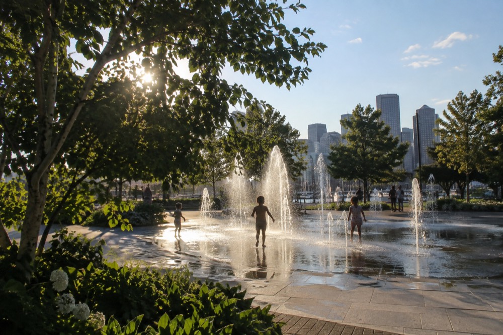 A splash fountain with children playing in shallow water beside a park path