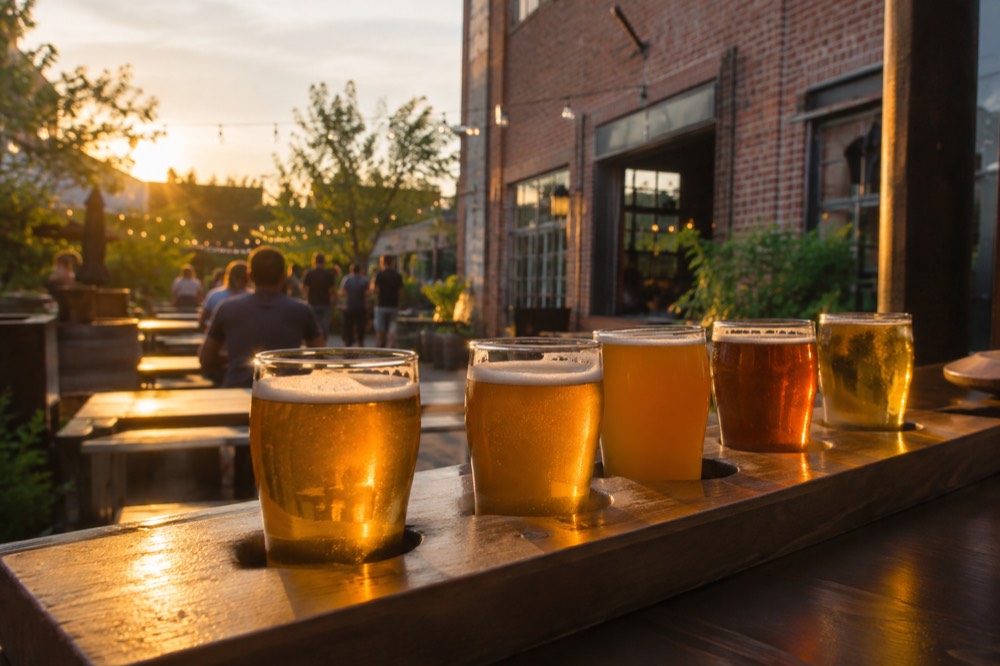 Glasses of golden beer lined up on a wooden tasting bar