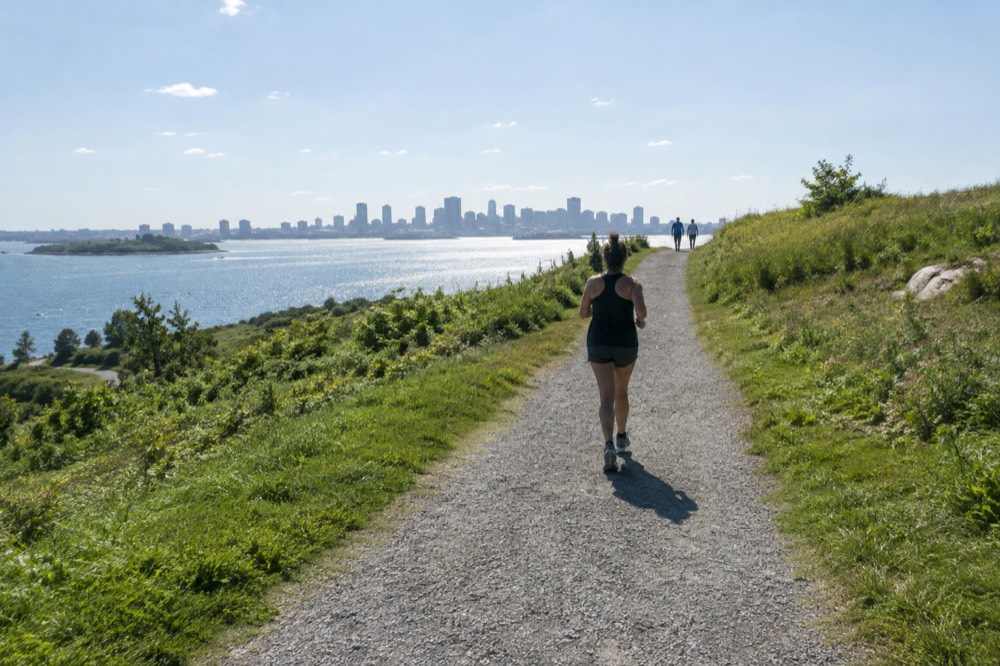 Gravel walking path climbing a grassy hill toward a panoramic view of Boston across the water