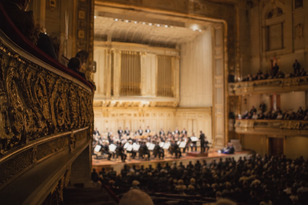 Ornate gilded balcony fronts and coffered ceiling inside a grand concert hall