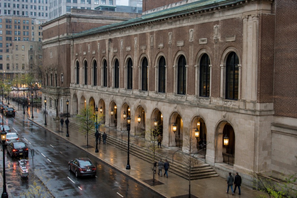 A brick and limestone concert hall facade with arched loggia along a city avenue