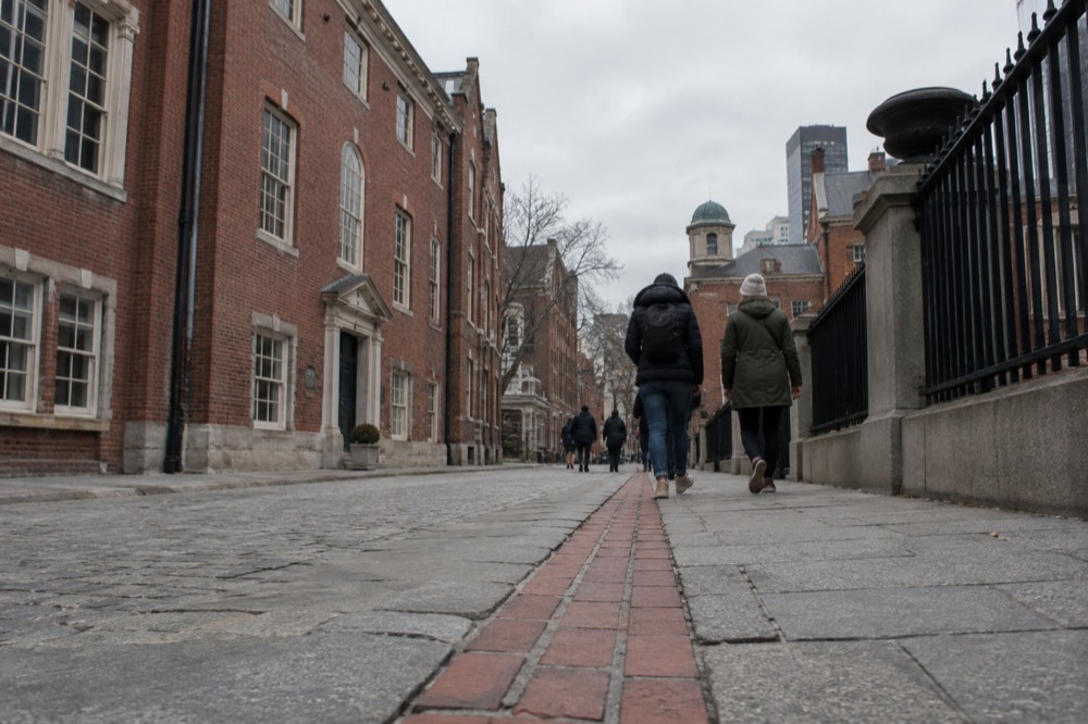 Visitors walking the red brick line of the Freedom Trail past historic Boston buildings