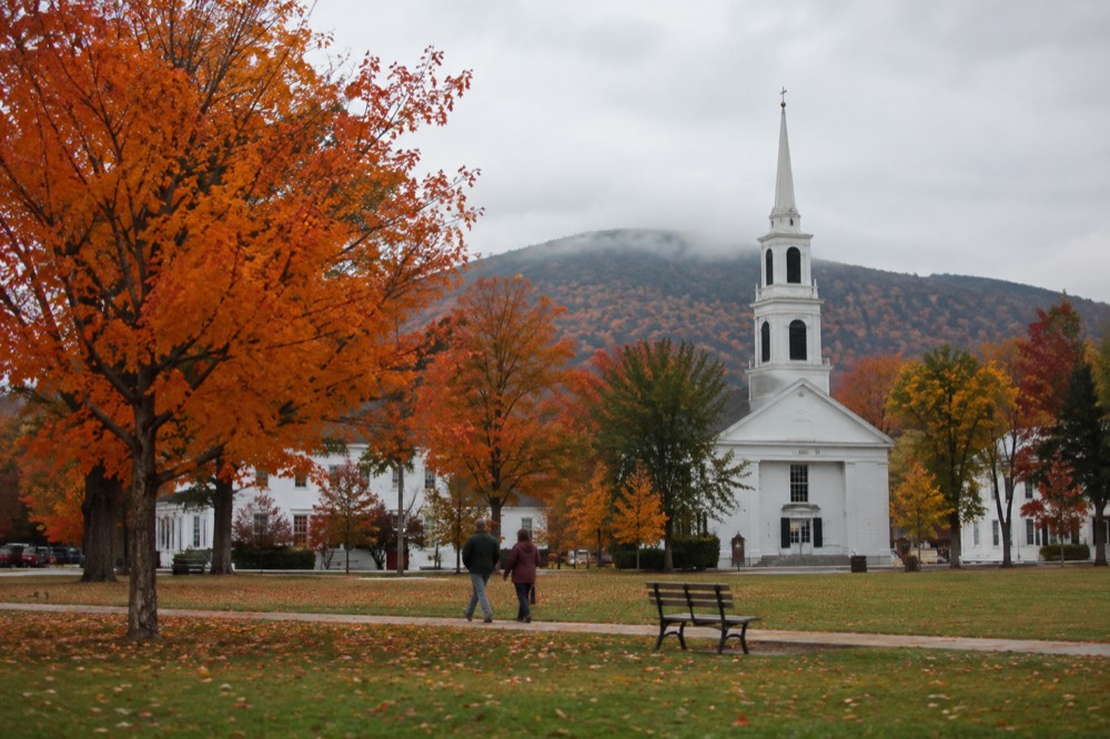 A New England town common with a white church and bright orange trees