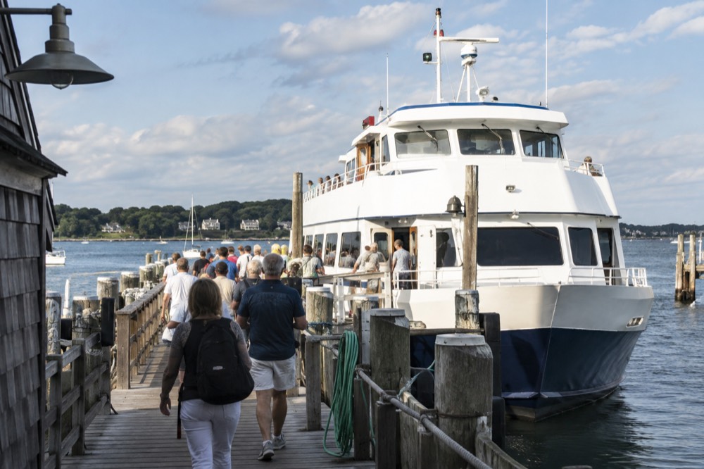A passenger ferry at a dock with travelers boarding on a summer day
