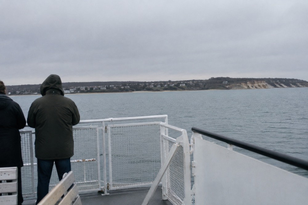 A ferry deck view of calm open water with a distant shoreline