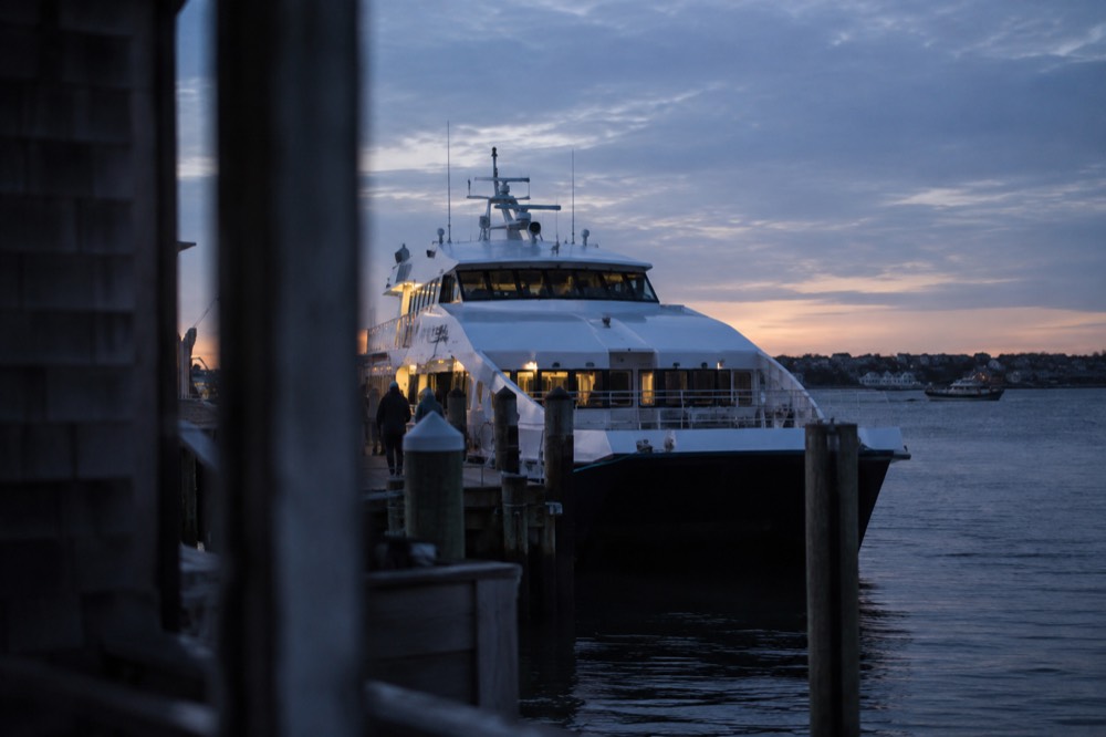 A high-speed passenger ferry tied up at a city waterfront dock in early morning light