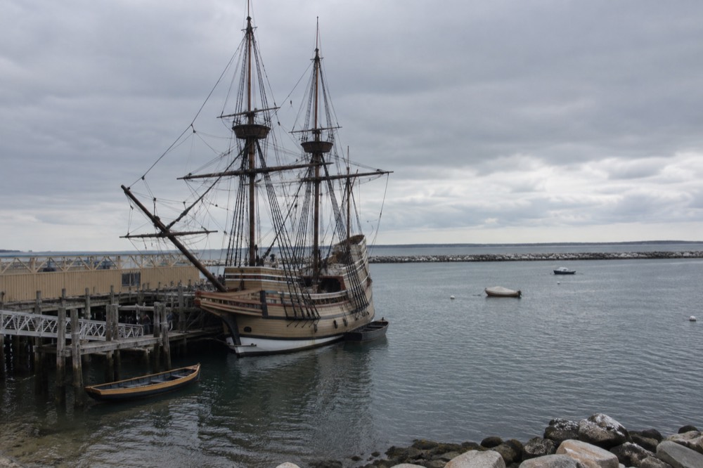 Mayflower II, a wooden sailing ship, moored at a waterfront dock in Plymouth harbor
