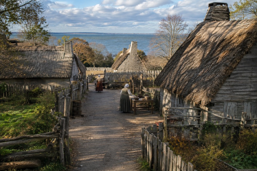 Costumed interpreters working beside timber-framed thatched cottages at a living-history museum