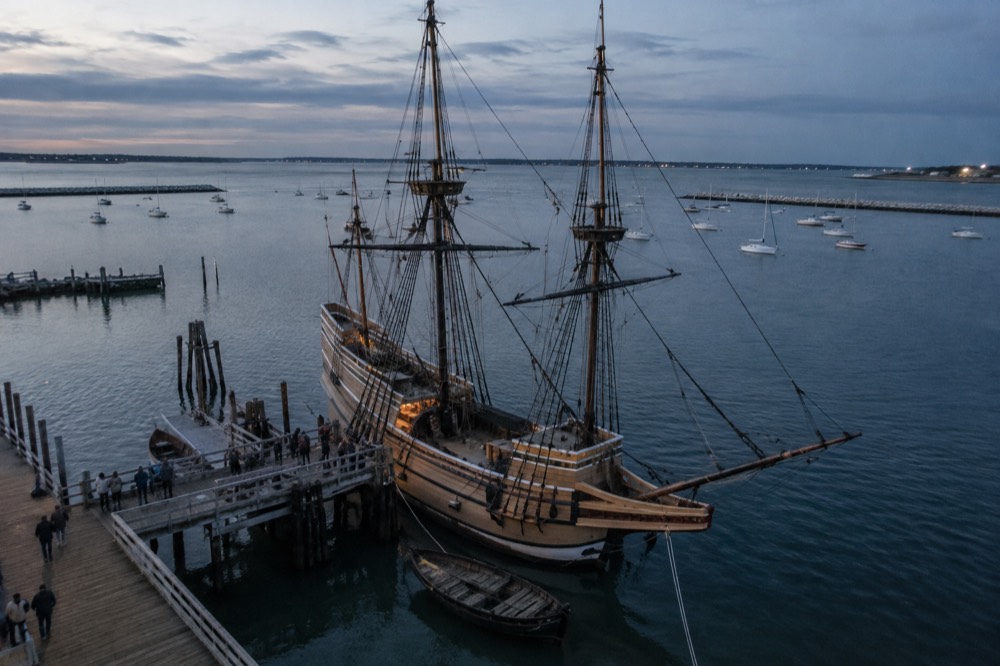 A wooden sailing ship with tall masts at a dock with visitors along the rail